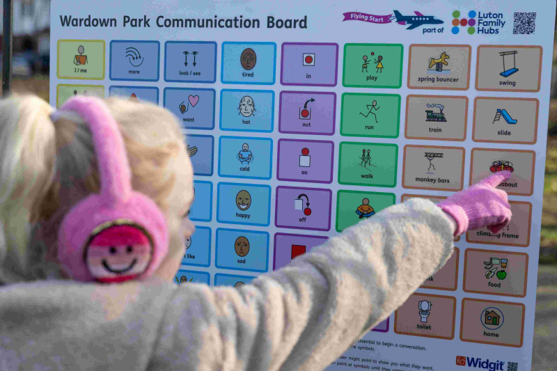 child pointing at communication board
