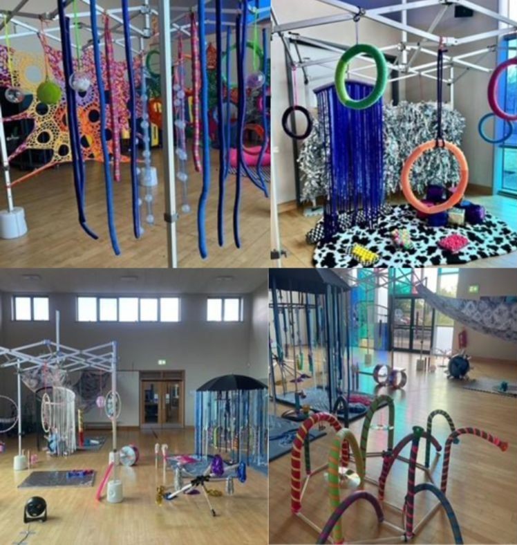 This image shows Play Sculptures which include hanging mobiles made from different materials, flexible arch structures, sensory toy stations, and draped materials, including a colourful crochet design.